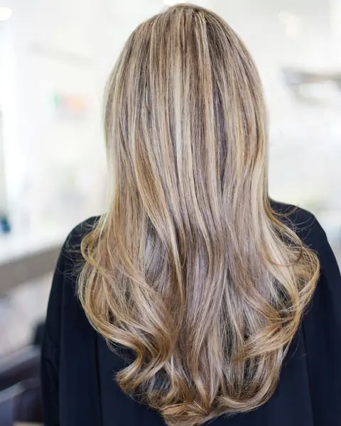 Beispielfoto: lange Haare mit Balayage in Honigblond, von hinten im Salon